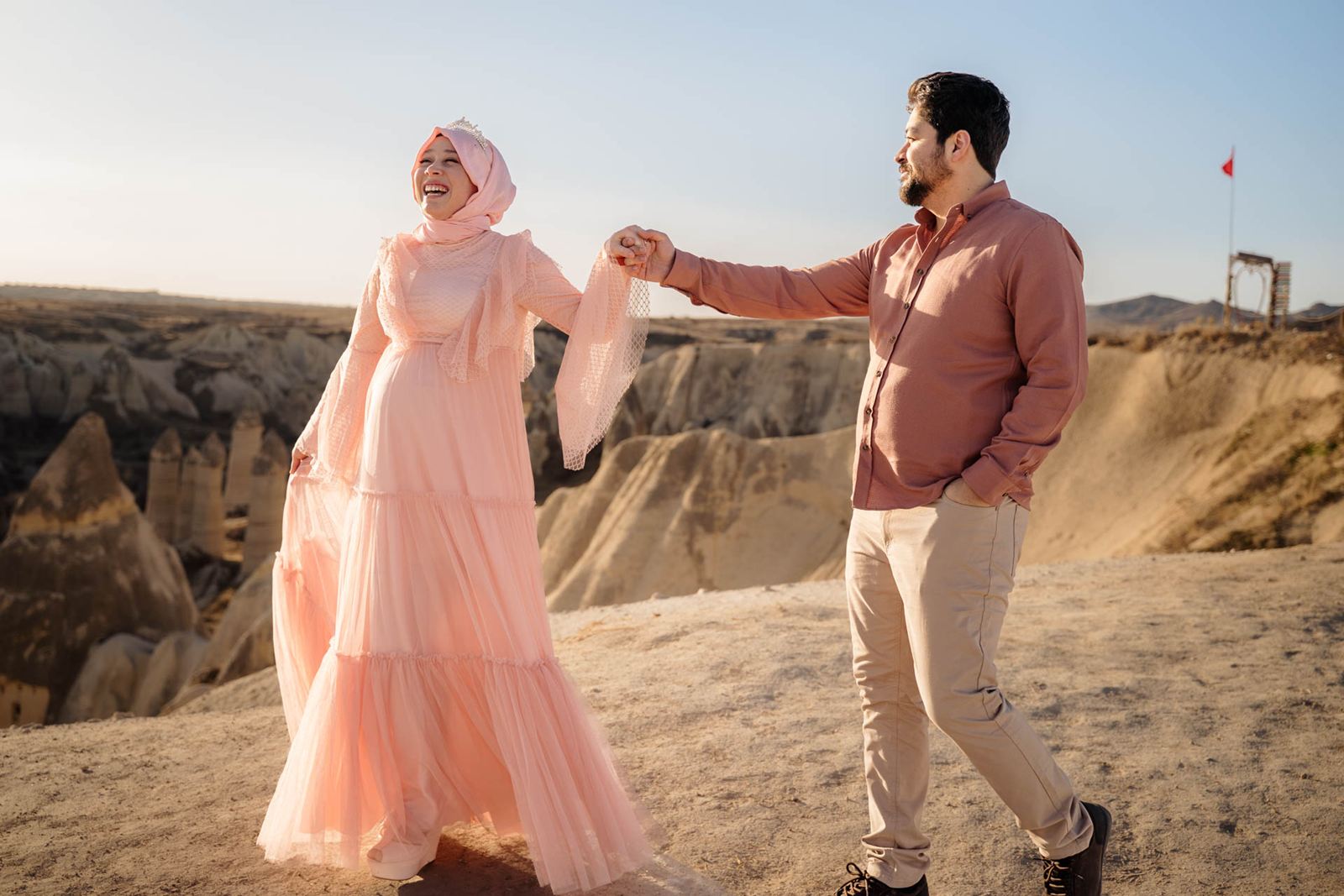 Laughing couple walking hand in hand in Cappadocia at sunset