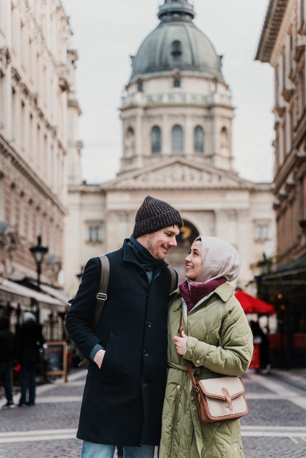 Couple embracing on a city street with a domed building behind them
